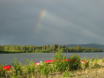 Scenic view of rainbow over lake against sky