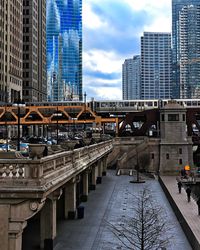 Bridge amidst buildings in city against sky