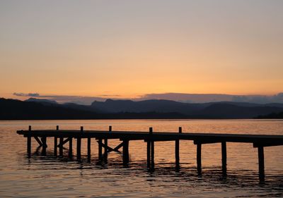 Silhouette pier on lake against sky during sunset