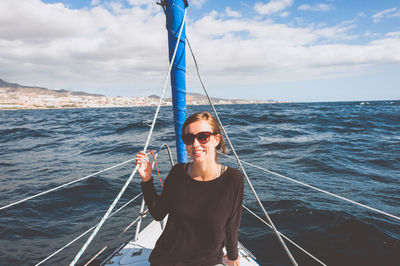 Portrait of smiling woman in sailboat against sky