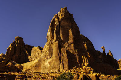 Low angle view of rock formation against clear blue sky