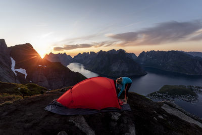 Mid adult woman building camp on mountain at reinebringen. lofoten, norway