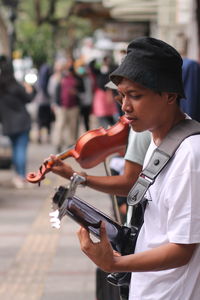 Young man playing guitar on the sidewalk in the city