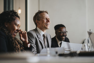 Smiling mature businessman discussing during meeting in board room at office