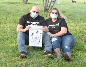 Man and woman sitting in field with masks baby announcement 