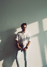 Portrait of young man standing against wall