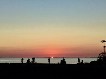 Silhouette people standing at beach during sunset