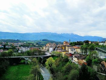 High angle view of townscape by mountains against cloudy sky