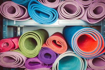 Various rolled exercise mats on shelves in gym