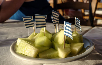 Small greek flags stuck in fruit slices on plate