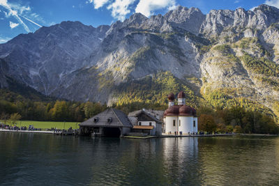 Built structure by lake and mountains against sky