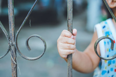 Close-up of child hand holding metallic railing