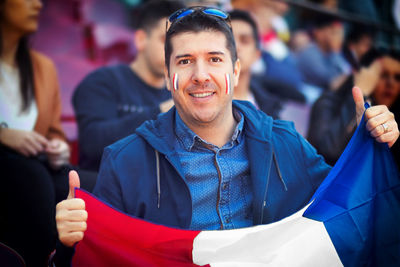 Happy supporter holding french national flag in hands at international football match