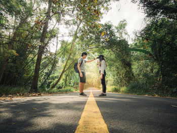 People standing on road amidst trees