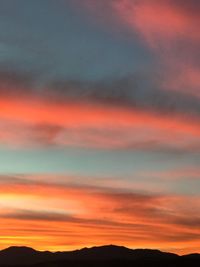 Scenic view of silhouette mountains against orange sky