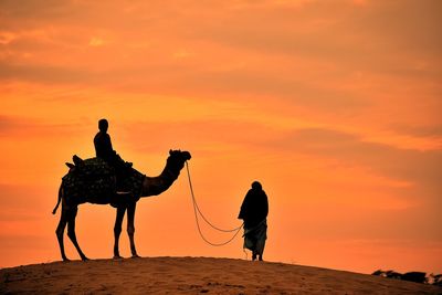 Silhouette of a camel and man in thar desert of jaisalmer.