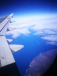 Aerial view of airplane wing over sea against blue sky