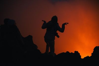 Silhouette woman gesturing while standing at volcano during night