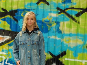 Portrait of girl standing against graffiti wall