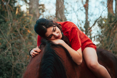 Smiling young woman sitting on horse in forest