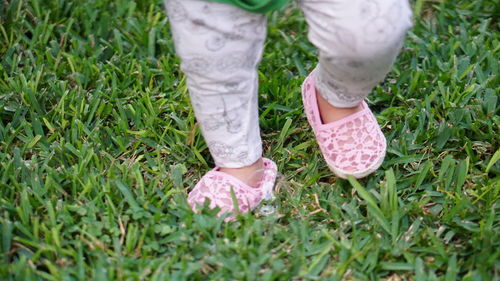 Low section of baby walking on grassy field