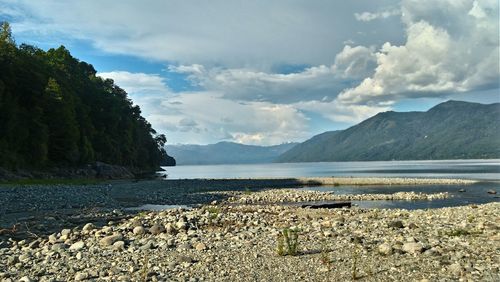 Scenic view of sea and mountains against cloudy sky