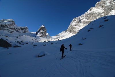 Rear view of people skiing on snowcapped mountain