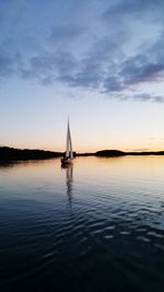 Sailboat sailing on sea against sky during sunset