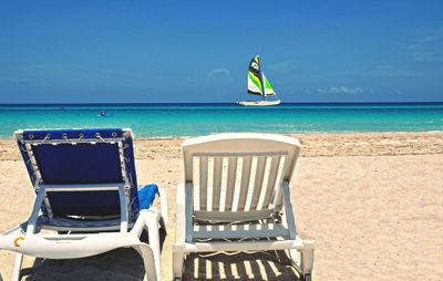 Chairs on beach against blue sky