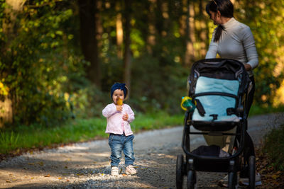 Full length of baby girl with mother on footpath