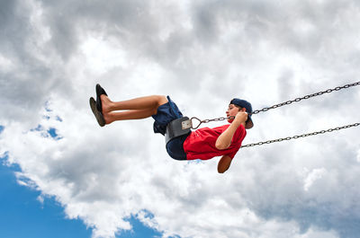 Side view of boy on a swing with only cloudy sky in the background.