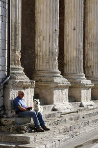 Side view of a woman sitting outside building