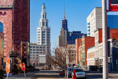 People on city street by buildings against sky