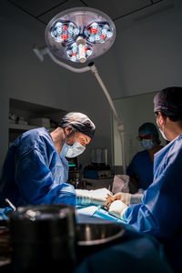 Veterinarian surgeons and nurses in uniform concentrating and operating dog using special equipment in operating room of contemporary hospital