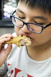 Close-up of boy eating chicken meat