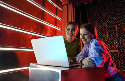 Young woman using mobile phone while sitting in building