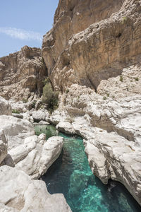 People swimming in the clear turquoise water of wadi bani khalid, sultanate of oman, middle east