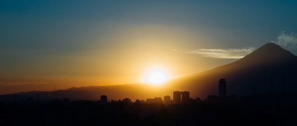 Silhouette buildings against sky during sunset