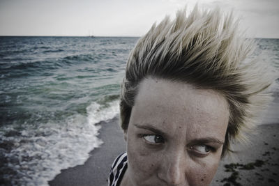 Close-up of woman with spiky hair looking away at beach
