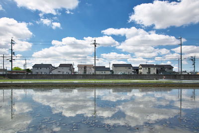 Reflection of houses in puddle against sky