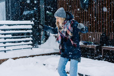 A young woman has fun and rejoices jumping during a snowfall as a child.