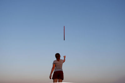 Rear view of woman standing against clear blue sky