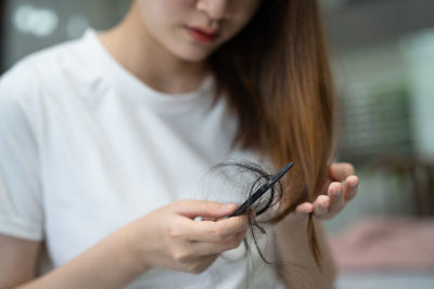 Asian woman have problem with long hair loss attach to comb brush.