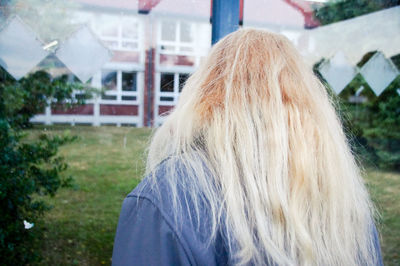 Rear view of woman with long blond hair in yard