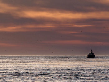 Silhouette ship sailing on sea against sky during sunset
