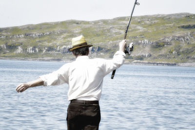 Rear view of man fishing by sea