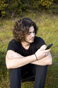 Man sitting on smart phone in grass