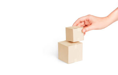 Cropped hand holding toy blocks against white background