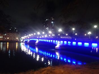 Illuminated bridge over river at night