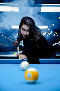 Young woman playing pool